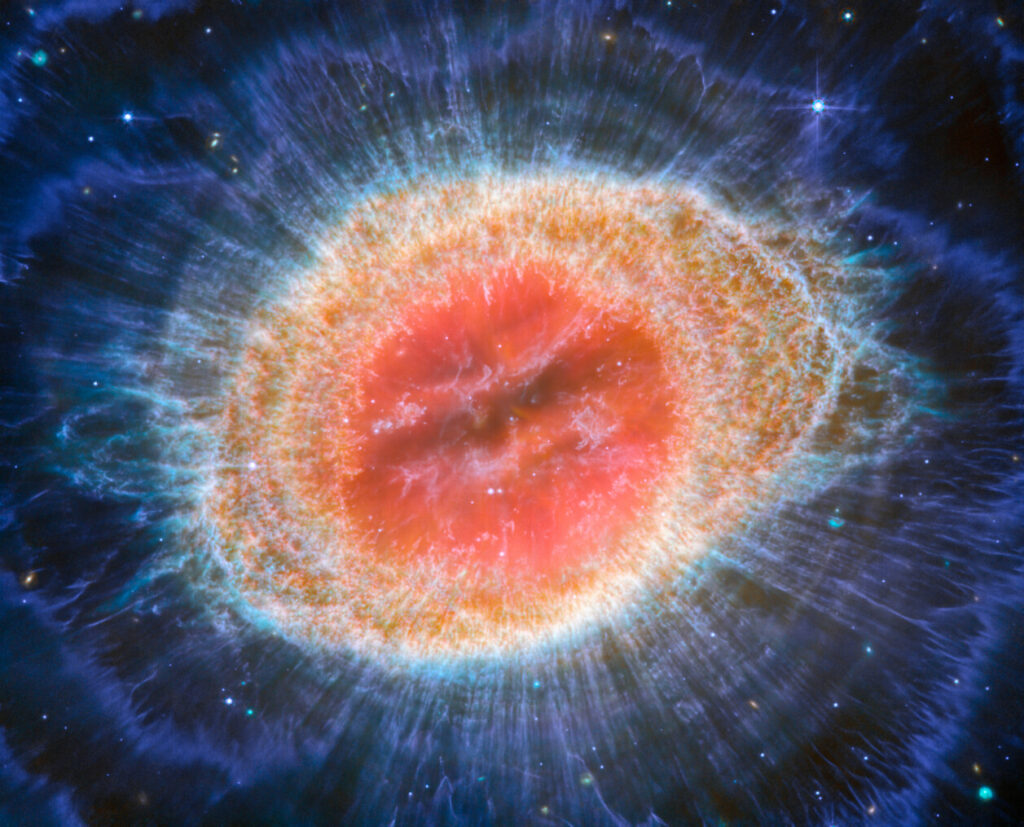 The NASA/ESA/CSA James Webb Space Telescope has observed the well-known Ring Nebula with unprecedented detail. Formed by a star throwing off its outer layers as it runs out of fuel, the Ring Nebula is an archetypal planetary nebula. Also known as M57 and NGC 6720, it is both relatively close to Earth at roughly 2,500 light-years away. This new image provides unprecedented spatial resolution and spectral sensitivity. In particular, Webb’s MIRI (Mid-InfraRed Instrument) reveals particular details in the concentric features in the outer regions of the nebulae’s ring (right). There are some 20,000 dense globules in the nebula, which are rich in molecular hydrogen. In contrast, the inner region shows very hot gas. The main shell contains a thin ring of enhanced emission fromcarbon-based molecules known as polycyclic aromatic hydrocarbons (PAHs). Roughly ten concentric arcs located just beyond the outer edge of the main ring. The arcs are thought to originate from the interaction of the central star with a low-mass companion orbiting at a distance comparable to that between the Earth and the dwarf planet Pluto. In this way, nebulae like the Ring Nebula reveal a kind of astronomical archaeology, as astronomers study the nebula to learn about the star that created it. [Image description: This image of the Ring Nebula appears as a distorted doughnut. The nebula’s inner cavity hosts shades of red and orange, while the detailed ring transitions through shades of yellow in the inner regions and blue/purple in the outer region. The ring’s inner region has distinct filament elements.]