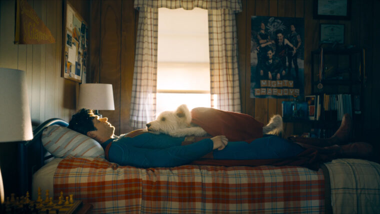 Foto de Krypto deitado em cima do Superman, que por sua vez aparece deitado no quarto de infância em Smallville (Warner/Reprodução)